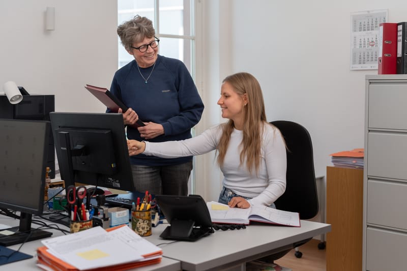 Zwei Mitarbeiterinnen der Kanzlei bei der Arbeit am Schreibtisch