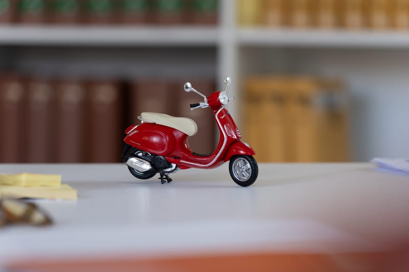 Modell einer roten Vespa vor einer Reihe juristischer Fachbücher
